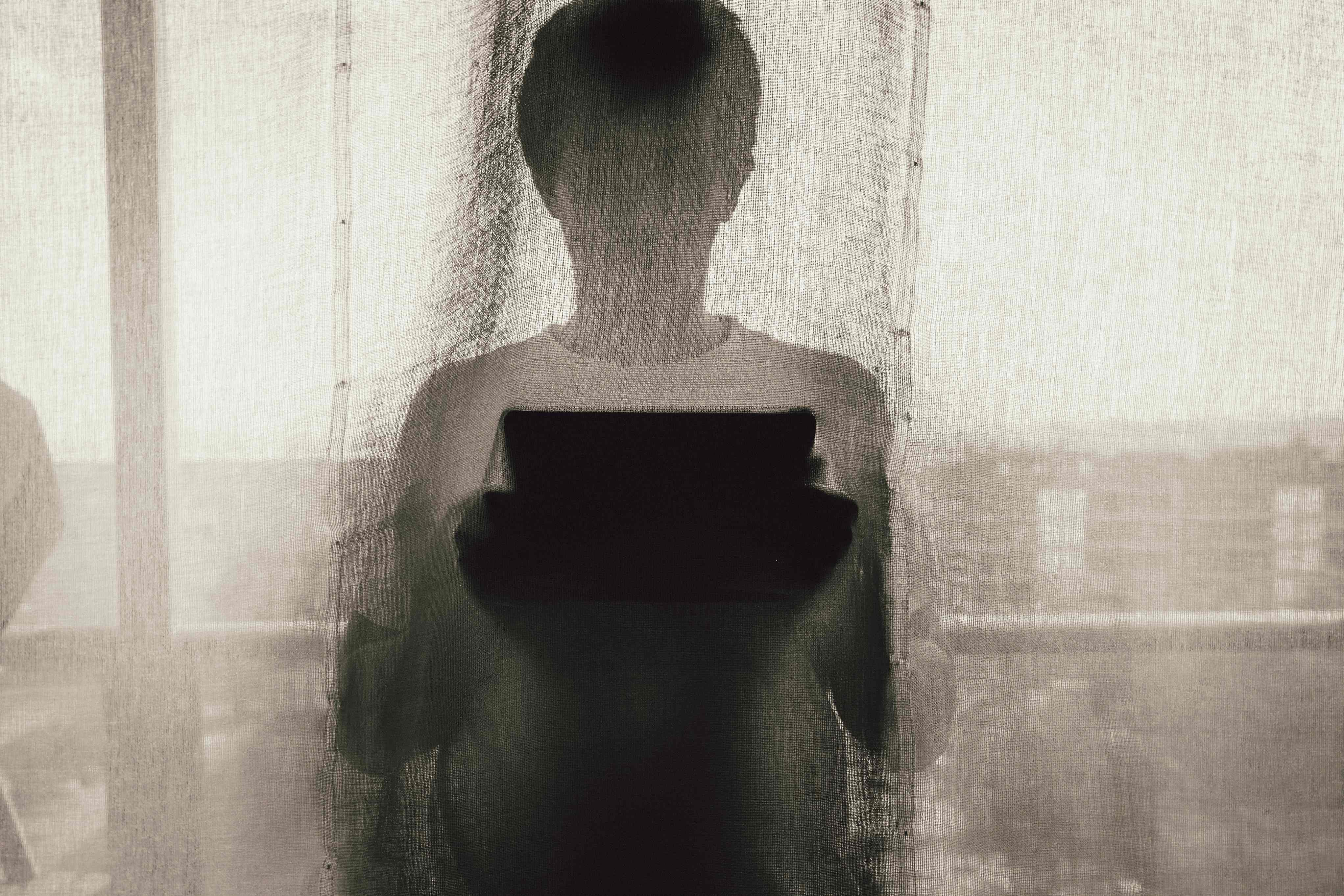 Juan Pablo Arenas Man Standing Holding A Tablet Behind Curtain